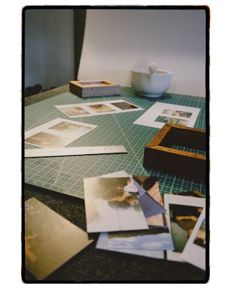Printed photographs and framing tools arranged on a green cutting mat