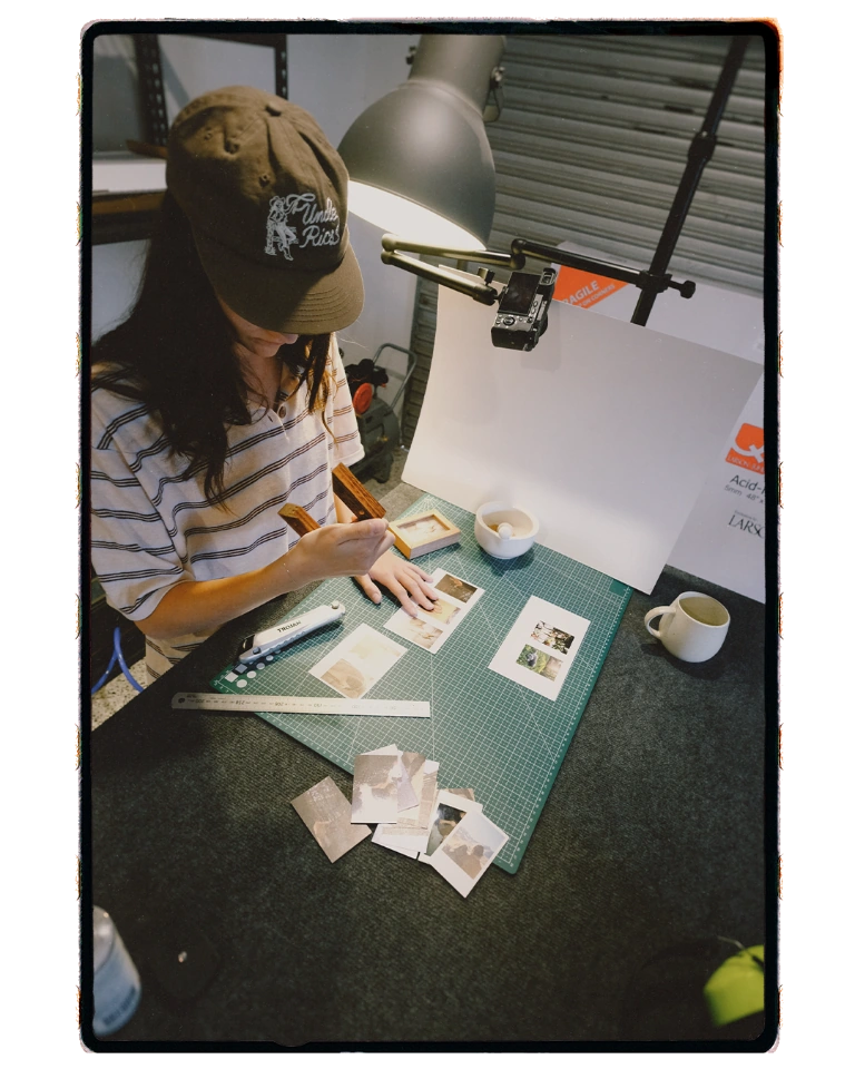 A craftsperson arranges printed photographs on the cutting mat