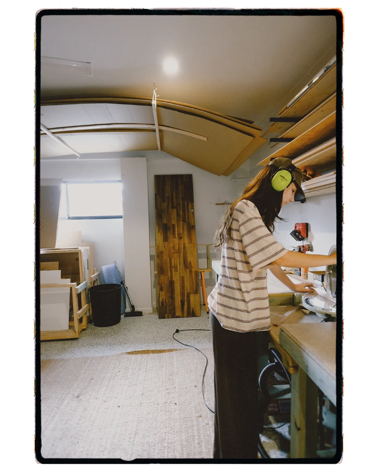 A craftsperson wearing hearing protection works at a saw in the Good Frame workshop