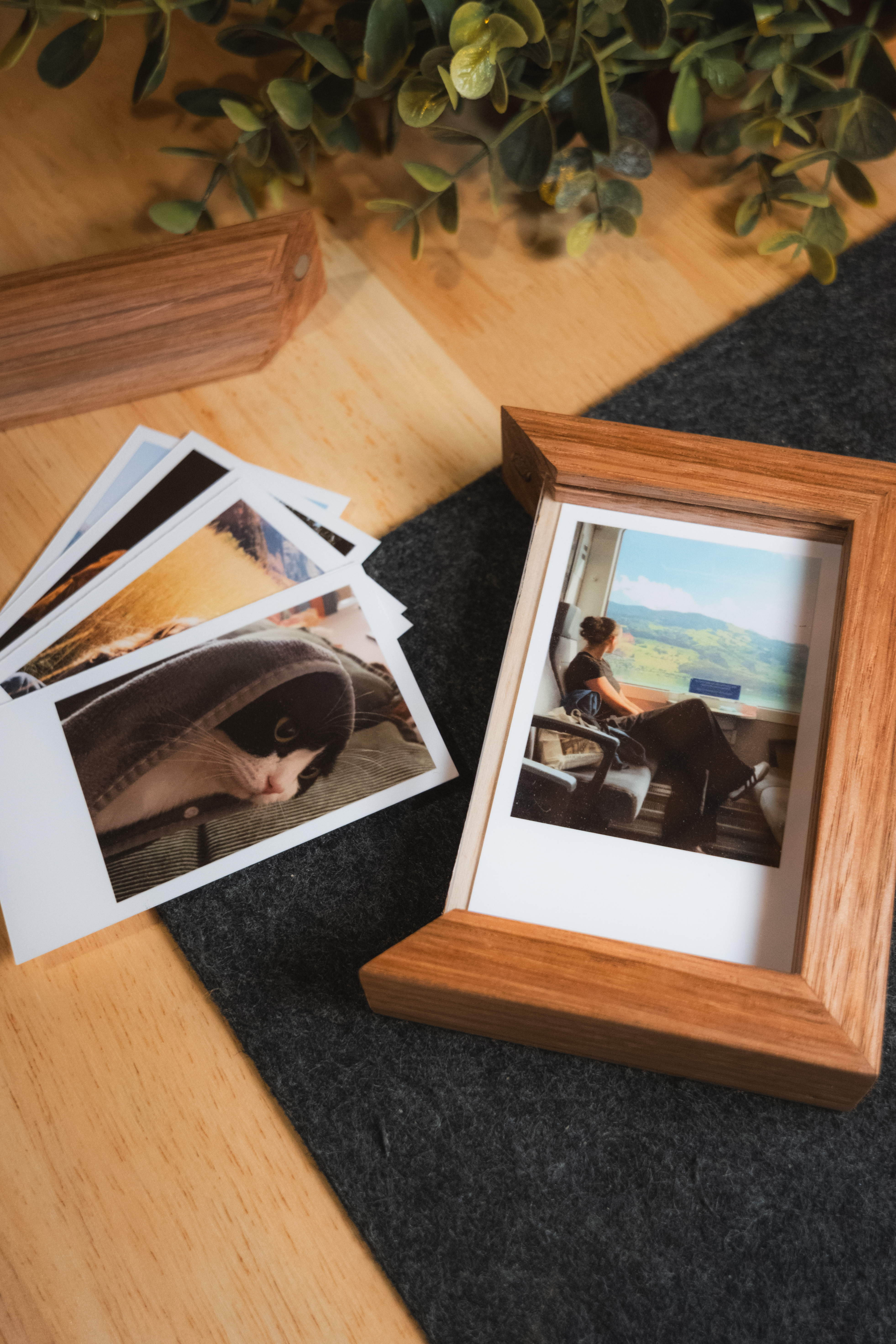Tiny timber frame and printed photos on a warm tabletop